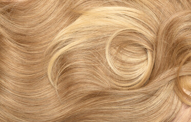 Blond hair close-up as a background. Women's long blonde hair. Beautifully styled wavy shiny curls....