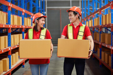 factory workers carrying corrugated box and taking together in the warehouse storage