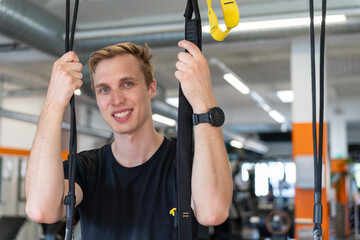 Portrait of caucasian athlete man smiling at looking at the camera while taking a brake after training in the gym