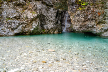 Crystal clear turquoise colored water of Pisnica river and small waterfall, Triglav National Park, Slovenia. Outdoor travel background