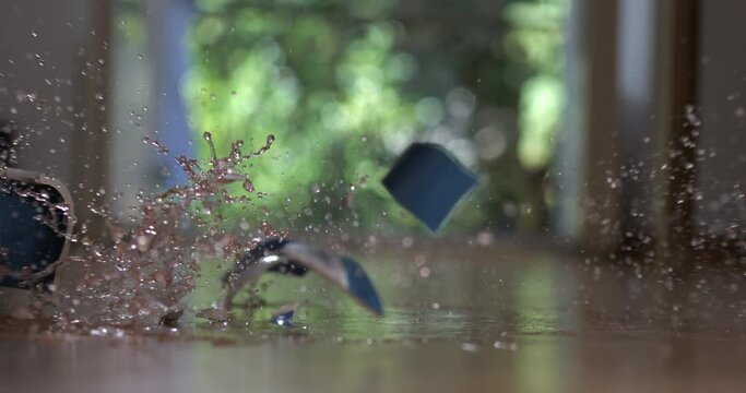 Tea cup falling to the ground and breaking into pieces in super slow motion captured with high speed camera. Accident concept of porcelain object shattering