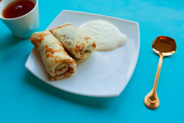 Tasty homemade pancakes with sour cream on white plate, top view