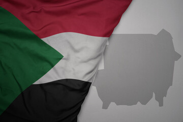 big waving national colorful flag and map of sudan on the gray background.