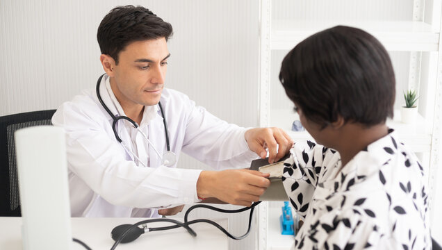 Hispanic doctor measuring African American patient's blood pressure. Person medical healthcare and wellbeing, the physician meet with patient at clinic concept.