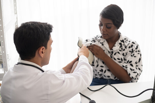 Hispanic doctor measuring African American patient's blood pressure. Person medical healthcare and wellbeing, the physician meet with patient at clinic concept.