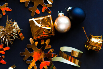 Golden decorations on black background. Flat lay, top view, copy space. Merry Christmas and Happy New Year