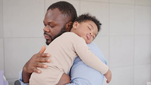 Loving African American dad embracing baby and baby girl sleeping on stepfather shoulder. Happy family with pleasure spending time at home, Being a father and Fatherhood family love relationship