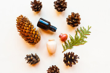 Cosmetic bottles, cones and spruce branches on white background, top view. Natural cosmetic products concept