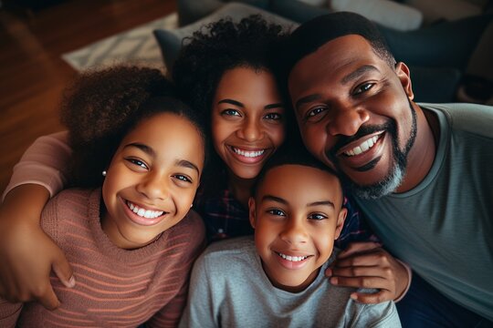 Portrait Of Happy Mature Couple With Child Relaxing On Sofa At Home. Middle Aged Black Woman With Husband And Children Smiling And Looking At Camera. Beautiful Family.