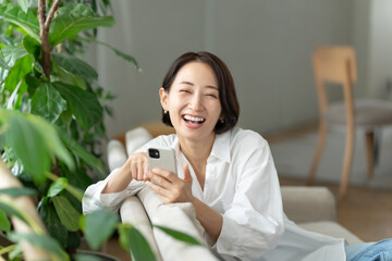 ソファに座ってスマホを使う女性