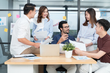 Diverse employees in office having fun during brainstorming while discussing ideas for new project, using laptop. Multiracial coworkers gather in meeting room discuss ideas in group of business people