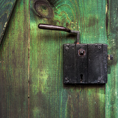 schwarzes Schloss mit Türgriff aus Eisen an einer grünen Tür aus Holz, quadratisch