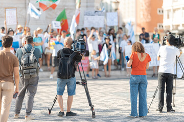 Reporters film a rally organized by Russians, Ukrainians and Belarusians against the war