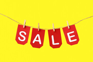 Flags with word SALE hanging on rope against yellow background