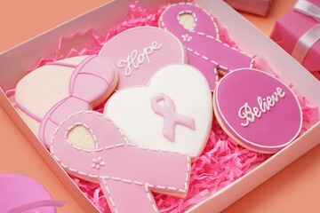 Cookies with ribbons and supportive words in box on color background. Breast cancer awareness...