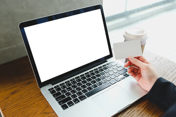 Hand holding a blank credit card and a laptop with a blank screen with space for text