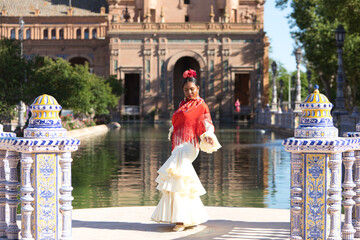 Young black woman dressed as a flamenco gypsy in a famous square in Seville, Spain. She is wearing...