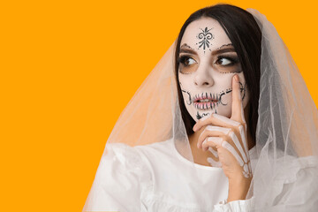 Beautiful young woman dressed as dead bride for Halloween party on yellow background