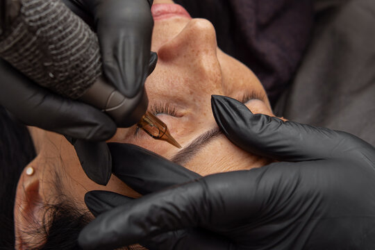 The process of permanent eyebrow makeup closeup. Master does eyebrow tattooing