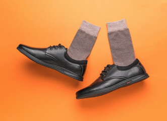 A pair of black men's shoes on an orange background. The concept of men's shoes.