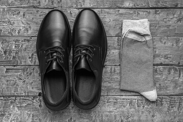 Black and white image of men's shoes and socks on a wooden background. The concept of men's shoes.