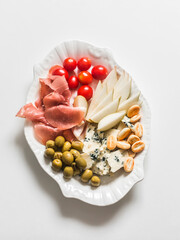 Tapas plate - ham, cheese, crackers, olives, cherry tomatoes - a delicious snack on a white background, top view