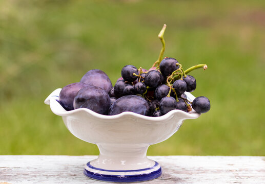 Blue plums and grapes in a bowl
