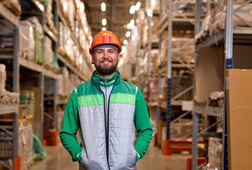 Handsome and happy professional worker in safety vest and hard hat smiling with arms in pocket,...