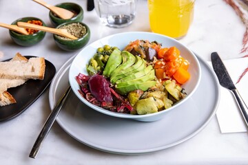 A white plate topped with a healthy salad next to a glass of orange juice