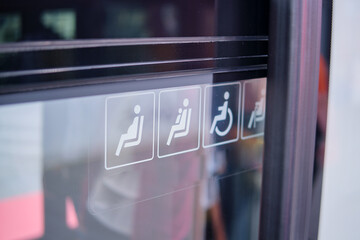 Close up of disabled sign on the glass door of a transport. Interior with seats for disabled...