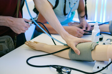 Doctor measuring blood pressure of a training dummy in hospital. Healthcare and medical concept.