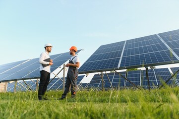 The solar farm(solar panel) with two engineers walk to check the operation of the system,...