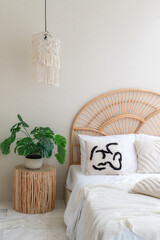 White pillows on wooden weave bed in minimal bedroom interior with green plants. Real photo