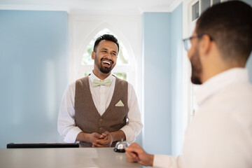 Middle Eastern Receptionist Man Laughing Communicating With Guest At Hotel