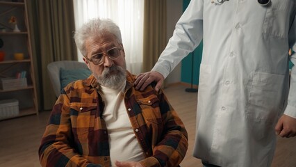 Medium shot of a handicapped eldery patient on a wheelchair having a medical check up at home. The...