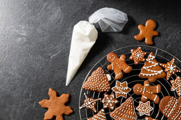 baking, cooking, christmas and food concept - close up of iced gingerbread cookies and pastry bag on black table top