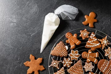 Foto op Plexiglas baking, cooking, christmas and food concept - close up of iced gingerbread cookies and pastry bag on black table top © Syda Productions