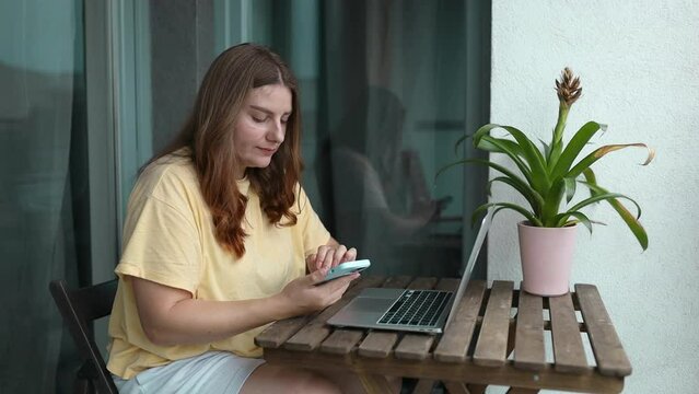 Happy blonde senior woman enjoying online communication on smartphone, holding digital gadget, laughing, talking on video call, using app while standing on balcony, Internet service, watching content