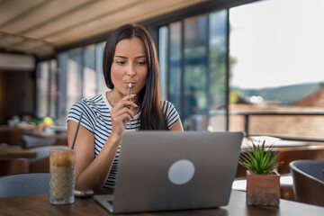 One woman sitting in cafe and holding electronic cigarette and working on laptop,  modern lifestyle...