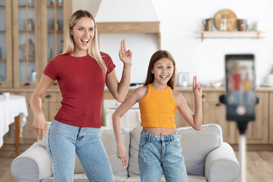 Positive mom and daughter kid dancing recording video on phone
