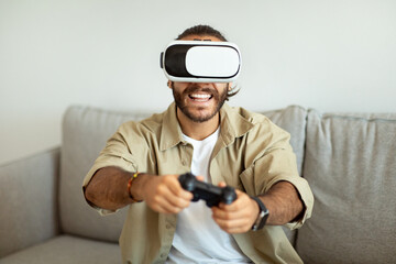 Happy young man playing video games at home, using VR