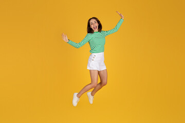 Fototapeta na wymiar Emotional carefree young brunette woman jumping in the air