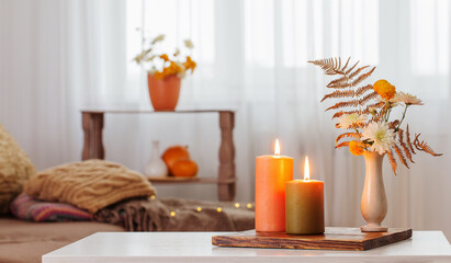 Fototapeta na wymiar burning candles with autumn decor on white table at home