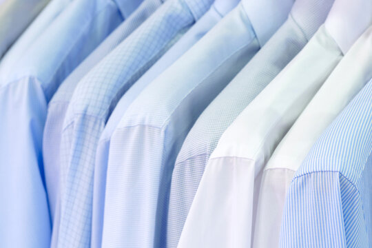 Closeup photo of Men's shirts hanging. Clothes hang on a shelf . Cloth Hangers with Shirts. Men's business clothes