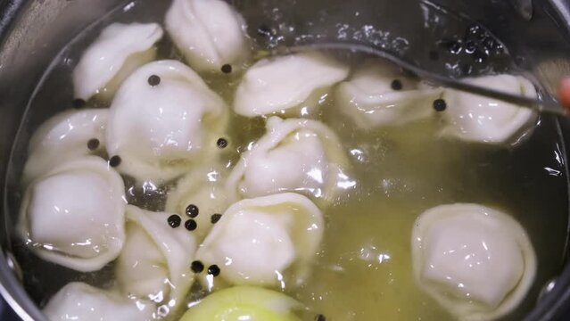 Taking out the cooked meat dumplings from the pot. Ready dish. Pelmeni are the traditional national Russian cuisine. Italian ravioli. Semi-finished food. Concept of fast tasty family dinner cooking.