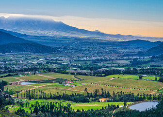 Aerial shot of Franschhoek wine valley surounded by mountains during sunset, Western Cape, South Africa