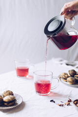 Pouring hibiskus hot tea from glass tea pot into glass cup © Nelli Kovalchuk