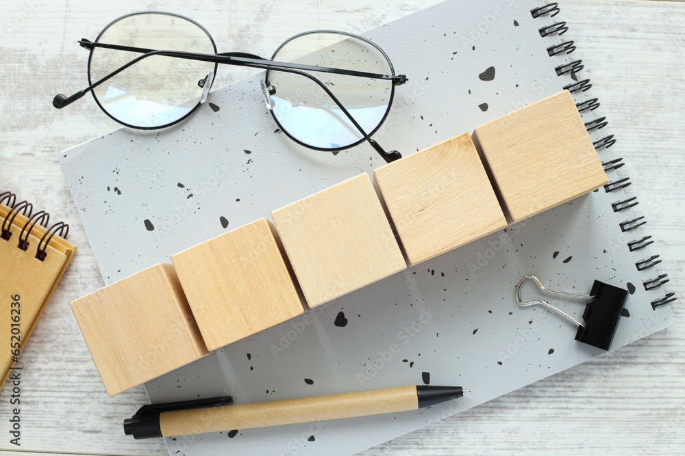 Poster five wooden blocks. office desk with a gray notepad. top view with copy space, flat lay. glasses and