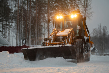 large tractor clearing the street after a snowfall in the suburbs, selective focus, blurred focus of construction equipment