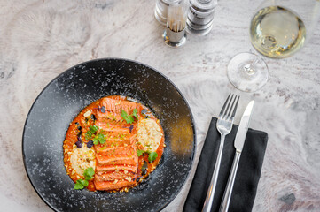 Salmon tataki in sauce with peanuts and herbs on a marble table in a restaurant